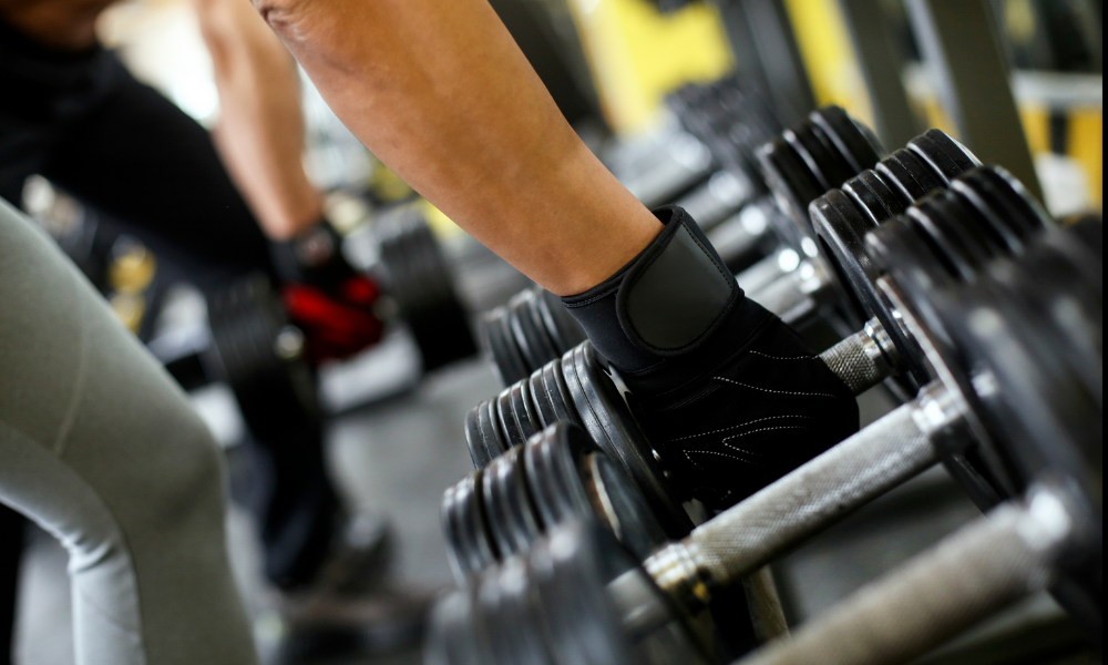 person picking up a dumb bell from a weight rack